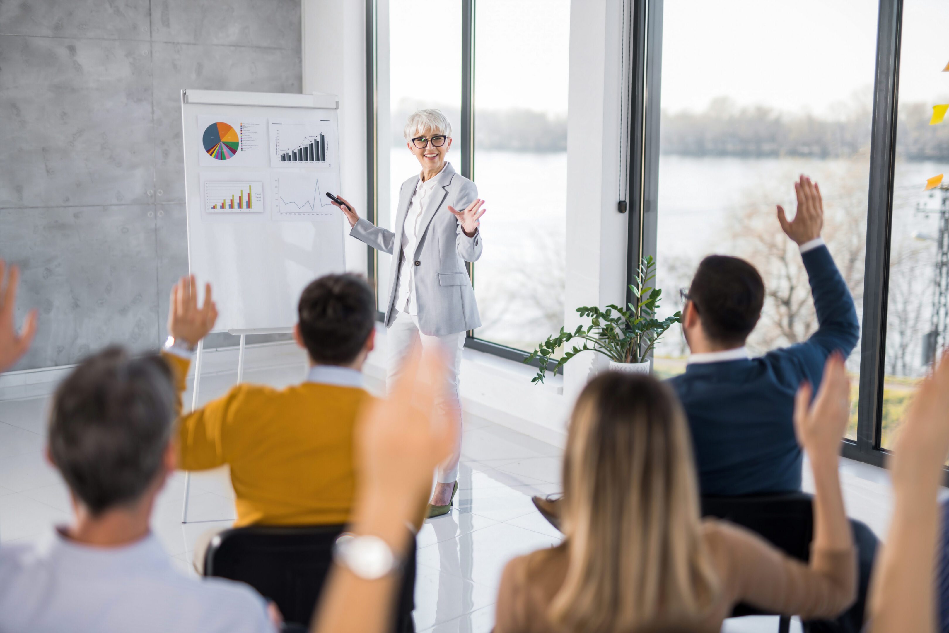 Presentation with audience raising hands, office setting.