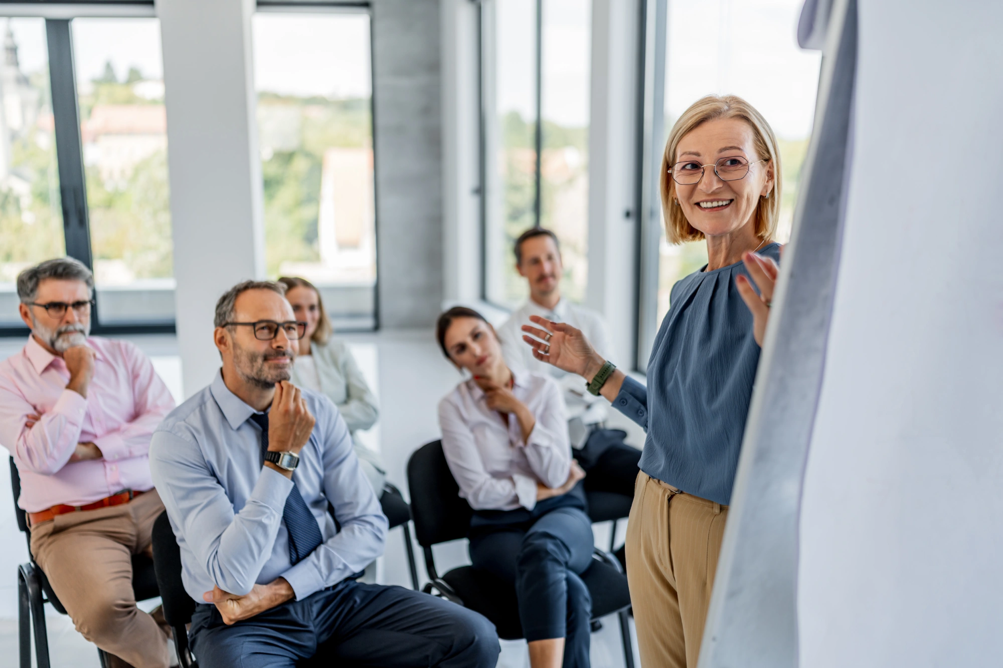 Businesswoman presenting to attentive colleagues in office.