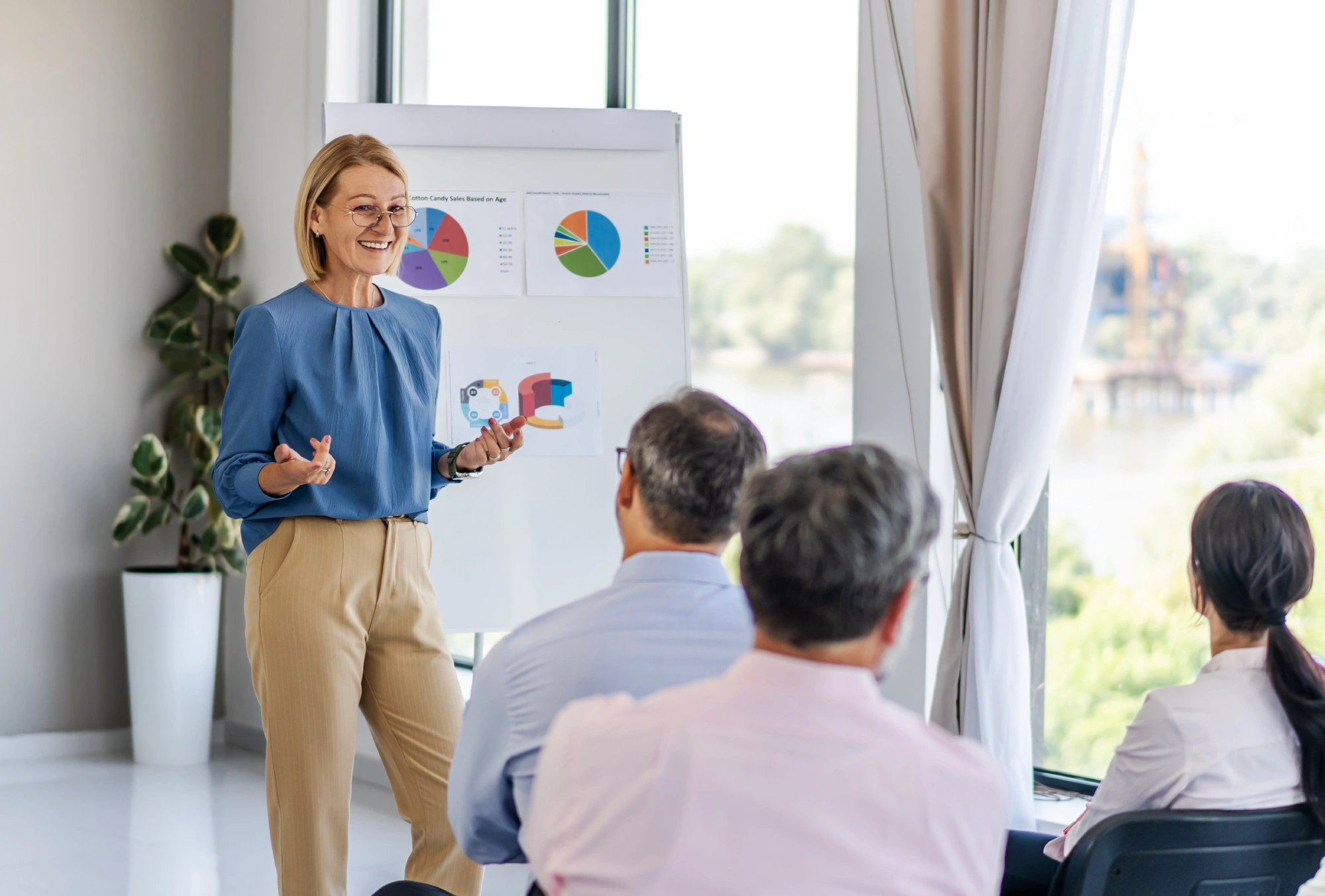 Woman presenting charts to seated audience.